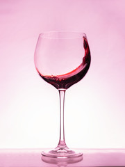 Red wine splashing a wave in a glass.