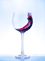 Red wine splashing a wave in a glass.