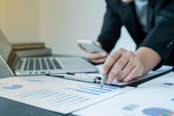 business female is sitting at a desk and calculating financial graph that show results