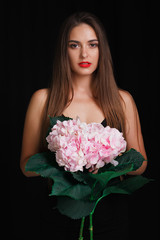 Brunette on a black background with a bouquet of large beautiful flowers