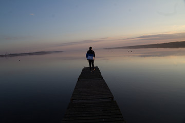 Fototapeta premium silhouette of man standing on the pier