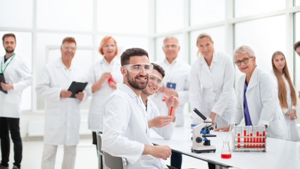 Fototapeta na wymiar smiling scientist sitting at a laboratory table .