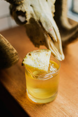 An iced cocktail in rocks glass garnished with pineapple and coconut