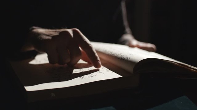Someone is leafing through old book in dark