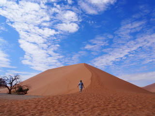 A woman barefoot up a beautiful sand Dune 45, Namibia