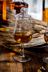 Tasting glasses with aged Scotch whisky or bourbon on old dark wooden vintage table with barley grains