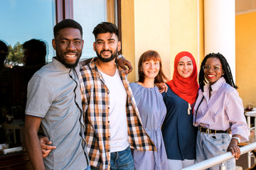 Multiracial young friends posing at the balcony of cafe.