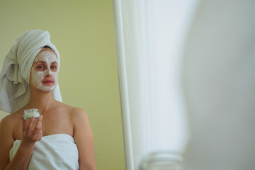 Woman after bathroom applying spa mask on her face