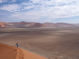 Fototapeta na wymiar A woman barefoot down a beautiful sand Dune 45, Namibia