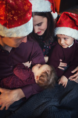 A young Caucasian family in Christmas hats. Home comfort and warm relationship in the family.