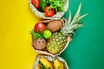 Eco shopping bags with organic fruits and vegetable on yellow background.