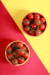 red cherry tomatoes on white marbel background on colorful red background on colorful red and yellow background