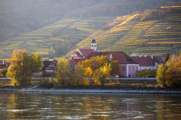 autumn view of small austrian village on a river bank