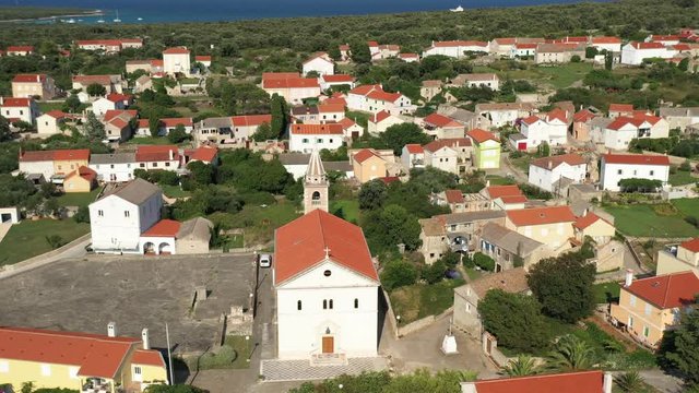 Flying over a church in the middle of the Olib Island Town in Croatia - aerial