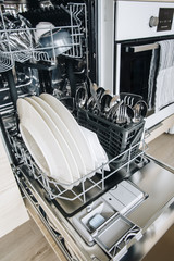 Blue colorful dishwasher detergent tablet for dishwashing machine. Open dishwasher with clean glasses and dishes close-up.