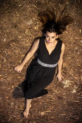 young woman in a black dress on the grass in the forest