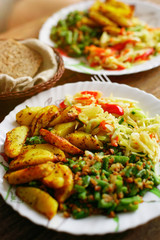 Food on a plate. Delicious and delicious homemade lunch: fried potatoes, string beans and a portion of salad. Top view