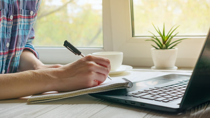 Education concept. Online studying from home office with black laptop and cup of coffee or tea