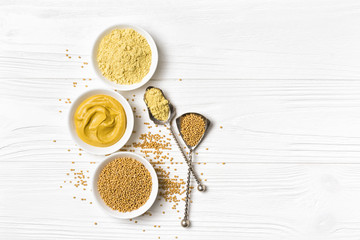 Set of yellow mustard sauce, powder and seeds in small bowls with silver spoons - obrazy, fototapety, plakaty