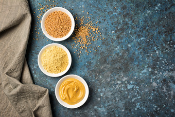 Set of yellow mustard sauce, powder and seeds in small bowls