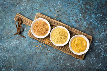 Set of yellow mustard sauce, powder and seeds in small bowls