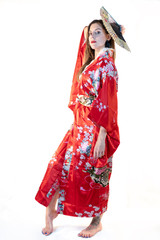 Girl dressed as a geisha posing in a red kimono in a photo studio