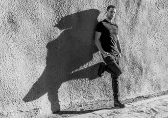 young and attractive man leaning on a wall reflecting his shadow