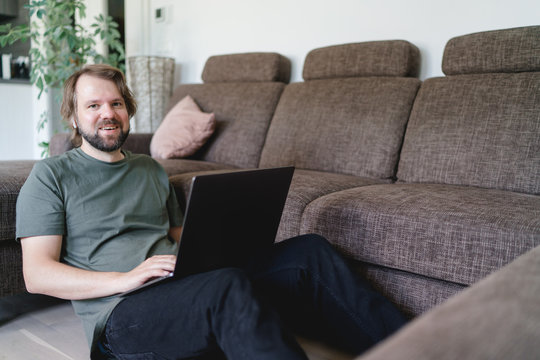 mann sitzt an der Couch und arbeitet im Homeoffice am laptop