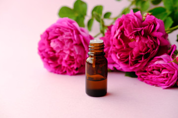 Bottles of essential oil and pink roses flowers