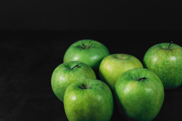 Group of organic green apples on a dark background with place for text. Organic eco food. Healthy diet. Freshly picked vegetables. Natural vitamin C. Some fruits. Farm organic fruits.