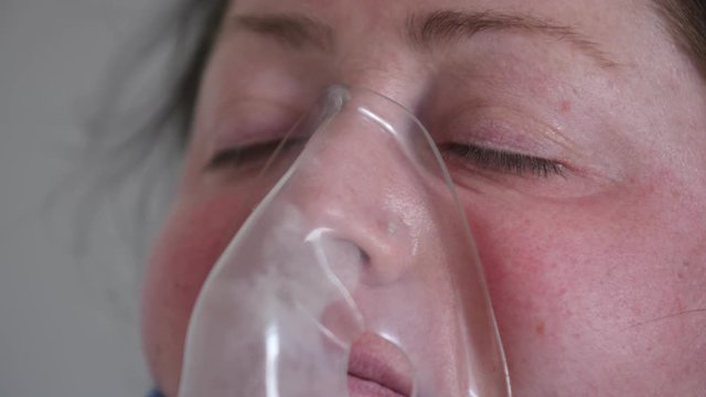 close-up face of woman with eyes closed in oxygen mask