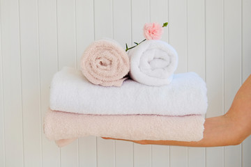 Housekeeping lady holding the set of folded and stacked towels. Room service woman holding a fresh clean laundry. Close up, copy space for text, background.