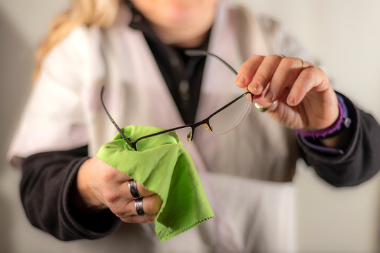 View of hands of eye doctor cleaning glasses with green cloth