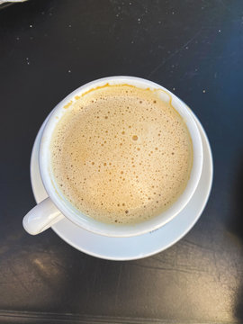 Cappuccino or latte with frothy foam, white coffee cup top view closeup isolated on vlack background. Cafe and bar, barista art concept.