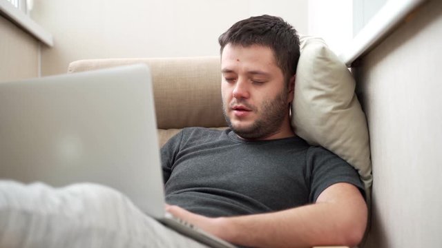 man works hard on modern grey laptop and falls asleep