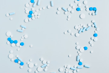 creative medicine compositions. the frame of tablets and capsules, different shapes on a light blue background. vitamins for skin, hair, and nails. flat lay, copy space
