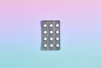 simple medicine concept. blister with pills on a gradient background. pink to blue stretch. top view, copy space