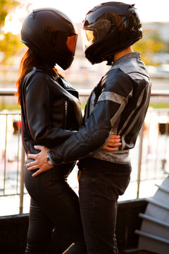 Couple of lovers man and woman in black helmets hugging Love