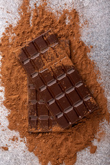 Two chocolate bars on cocoa powder. Top view.