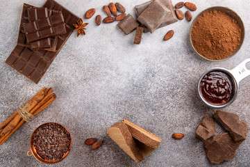 Assortment of different chocolate types and spices on concrete background. Top view, copy space.  Food background.