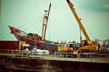 Crane picking up blue boat up in the air