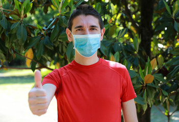 COVID-19 Optimistic sporty man wearing surgical mask on face during pandemic coronavirus disease...