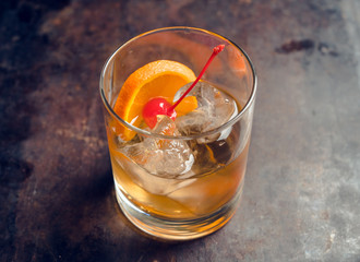 Old fashioned beverage with orange slices on rustic background. Selective focus. Shallow depth of field.
