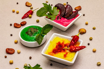 Hummus, healthy vegan (vegetarian) food. Assorted three types: classic, mint and beetroot. Edamame dry beans, pieces of pita bread, spices