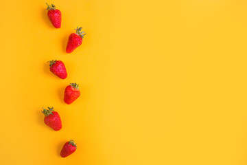 Pile of fresh strawberries on yellow background. Top view point.