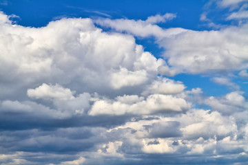 Cloudscape. Blue sky and grey clouds. Sunny day. Cumulus clouds.