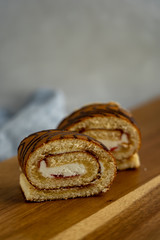 Two sponge roll slices are laying on wooden cutting board, closeup view
