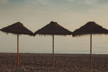 Three beach hat (parasol), in straw on beautiful sunset