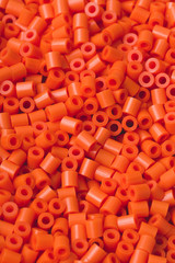 Obraz premium Closeup macro of hundreds of bright orange plastic fuse beads used for kids crafts