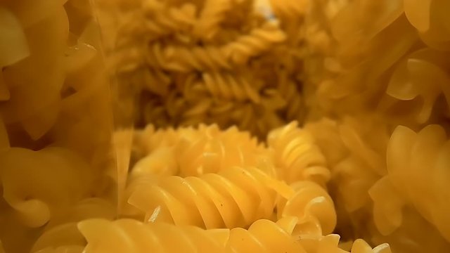 The camera moves slowly between transparent packages of dry pasta (fusilli), on a store shelf and ready to cook. Macro. Closeup. Shallow depth of field. Ultra small special camera